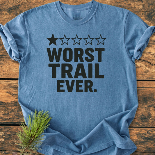 Heather-blue Worst Trail Ever - Vintage Wash Tee on wooden surface, featuring a one-star rating graphic and bold text. The T-shirt showcases a relaxed fit and durable double-needle stitching.