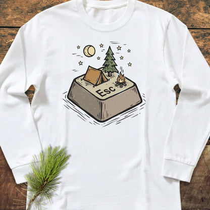 Escape Long-Sleeve Tee featuring a whimsical Esc key camping illustration with a tent, pine tree, and campfire under a moon and stars, laid on a wooden surface with a pine sprig.