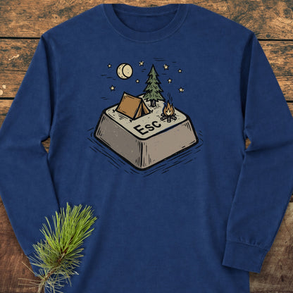 Escape Long-Sleeve Tee featuring a whimsical Esc key campsite illustration with a tent, pine tree, and campfire under a moon and stars, laid on a wooden surface with pine branch styling.