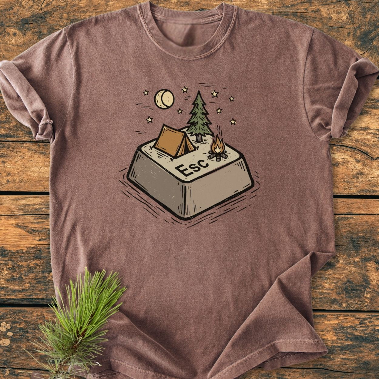 Escape - Vintage Wash Tee features a stylized “Esc” key as a campsite, with a tent, campfire, pine tree, crescent moon, and stars, printed on a brown Comfort Colors T-shirt.