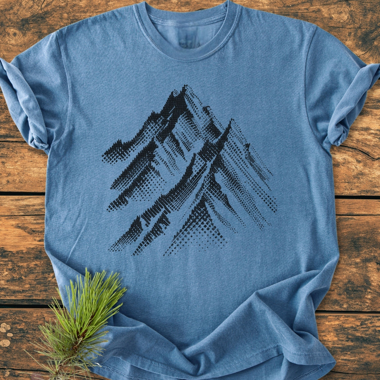 Take Me Higher - Vintage Wash Tee, heather-blue with a black mountain range graphic, laid flat on rustic wood. Features a cozy, relaxed fit with durable, double-needle stitching.
