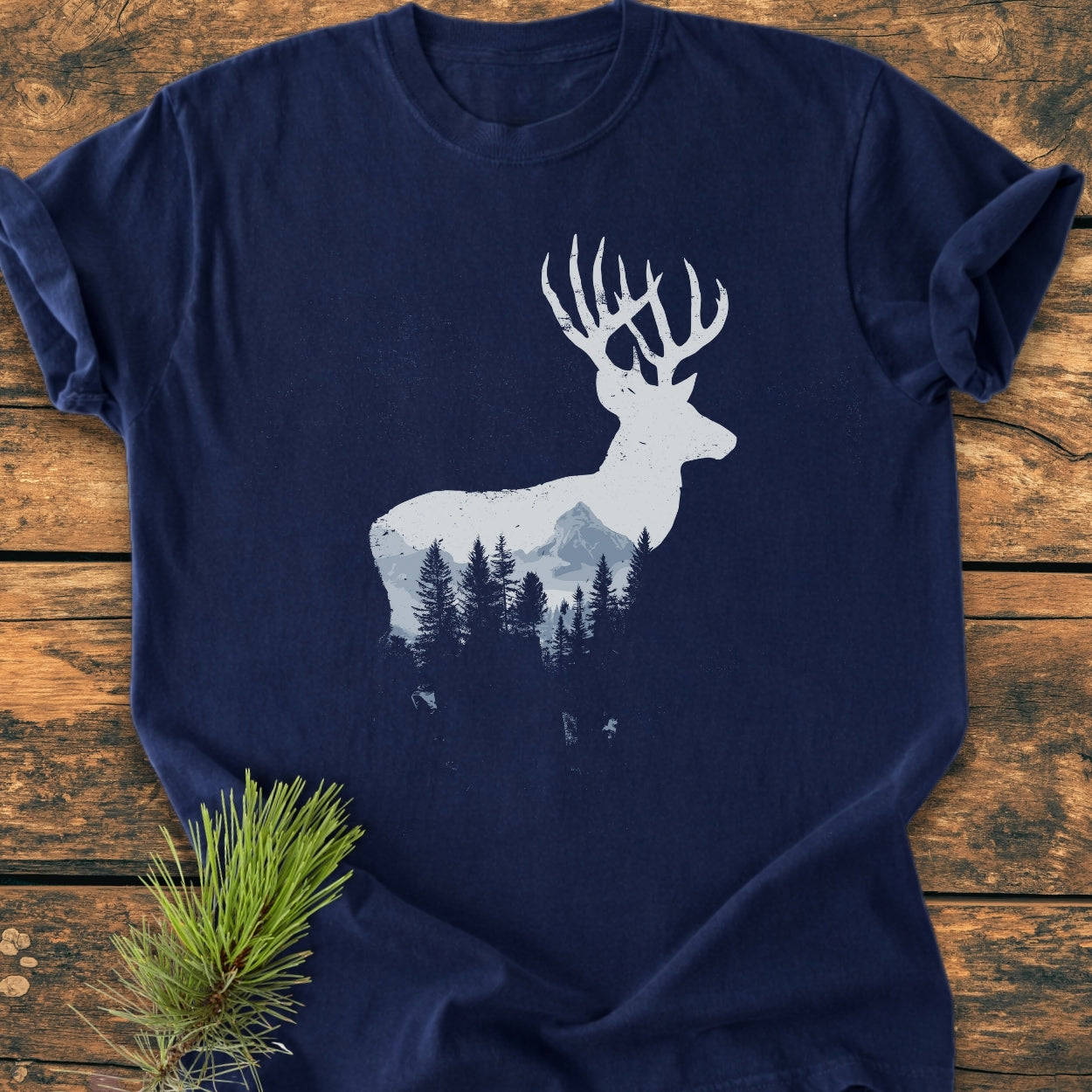 Deer Silhouette - Vintage Wash Tee featuring a white stag and mountain scene design, laid on wood. Made from soft, garment-dyed, pre-shrunk cotton, offering a relaxed fit and durable double-needle stitching.