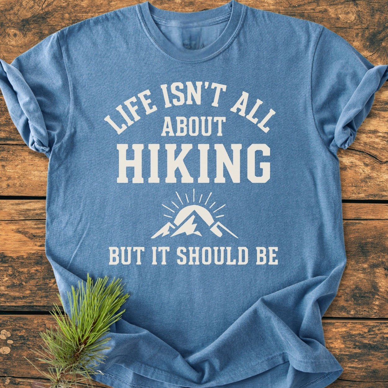 Life Isn't All About Hiking - Vintage Wash Tee displayed flat with bold white lettering and mountain graphic, made of soft 100% ring-spun cotton, with a relaxed fit. Pine sprig accentuates the design.