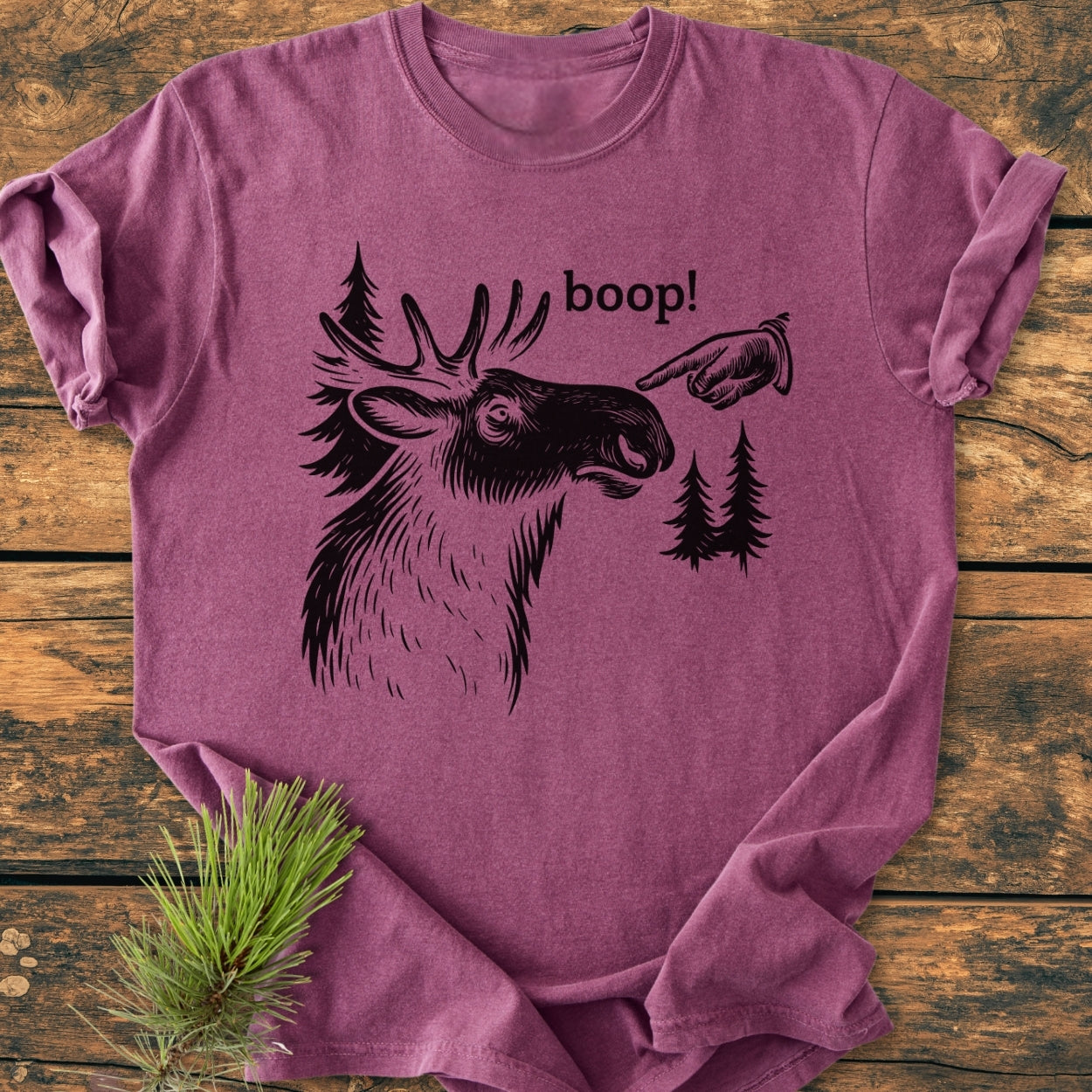 Heather-purple BOOP Moose Funny - Vintage Wash Tee features a stylized moose line-drawing with boop! above. Laid flat on a wooden surface, showcasing its relaxed fit and durable stitching.