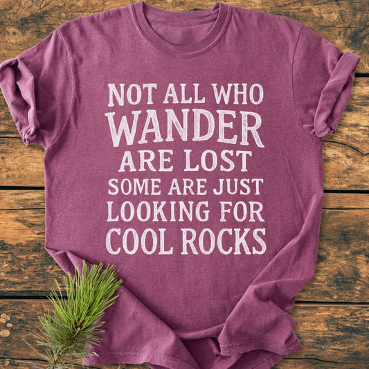Not All... Rustic Chalkboard - Vintage Wash Tee in heathered purple, folded on wood. Features bold white text and pine sprig detail. Made from soft, durable, pre-shrunk 100% ring-spun cotton.