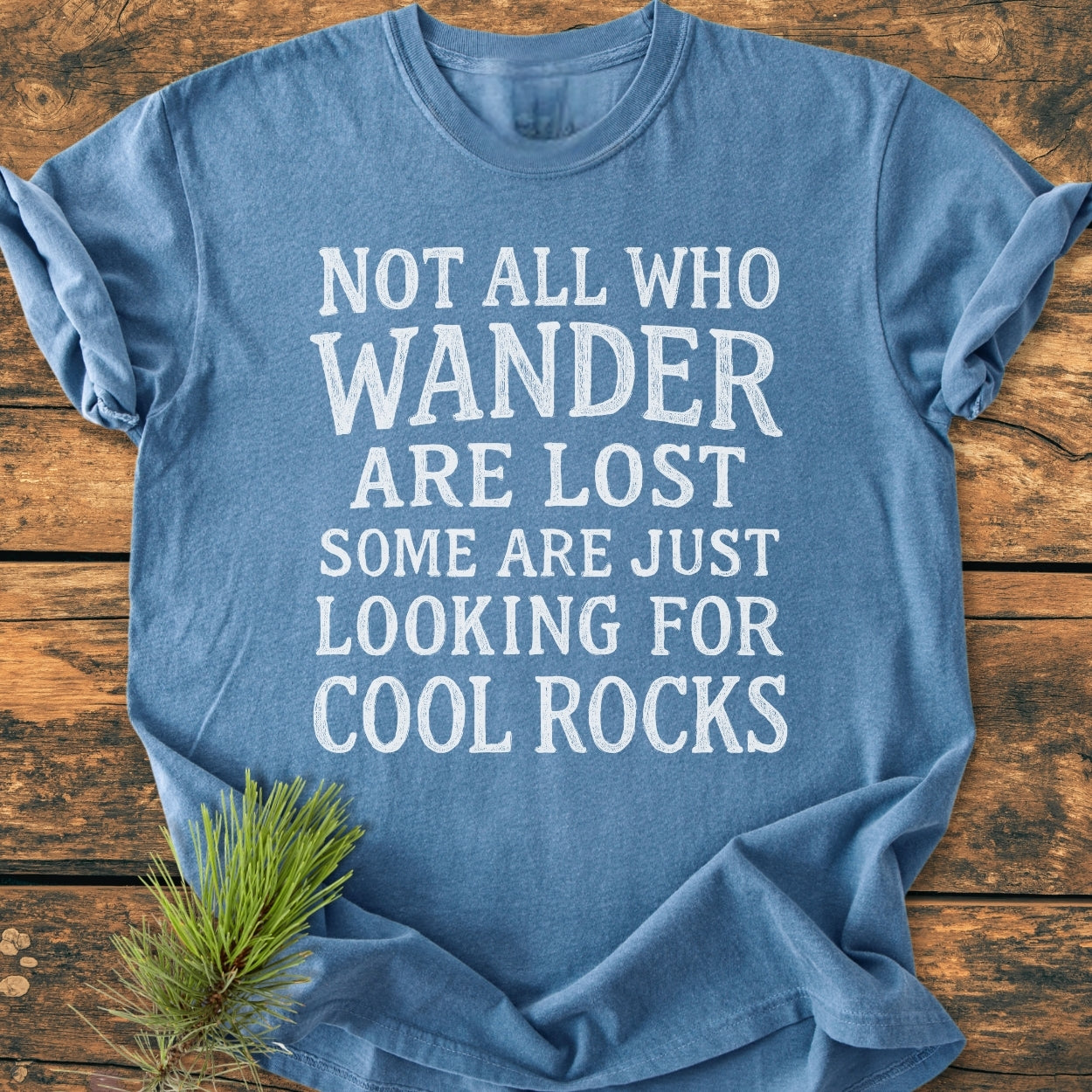 Heather-blue Not All... Rustic Chalkboard - Vintage Wash Tee on wood surface with pine sprig, featuring white block letters. Garment-dyed, soft-washed, 100% cotton tee with relaxed fit and durable stitching.