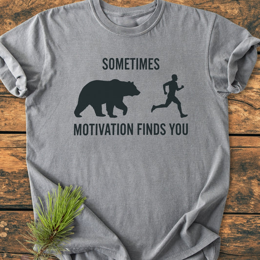 Sometimes Motivation Finds You - Vintage Wash Tee features a bear and runner graphic with text humor. This heather-gray T-shirt is laid flat, showcasing its relaxed fit and durable double-needle stitching.