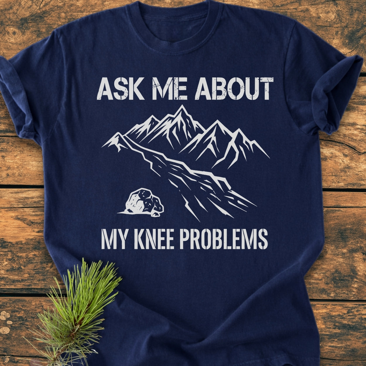Ask Me About My Knee Problems - Vintage Wash Tee featuring a mountain graphic and playful text on a navy-blue T-shirt, laid on wood. Crafted from soft, pre-shrunk 100% ring-spun cotton.