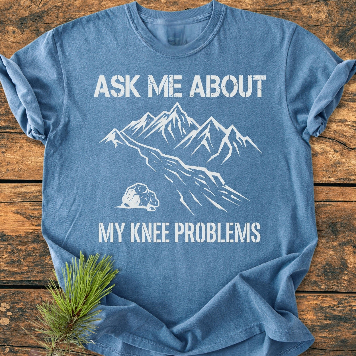 Heather-blue crew-neck T-shirt, titled Ask Me About My Knee Problems - Vintage Wash Tee, features white mountain line art and text on chest, showcasing a relaxed fit and durable, soft-washed fabric.