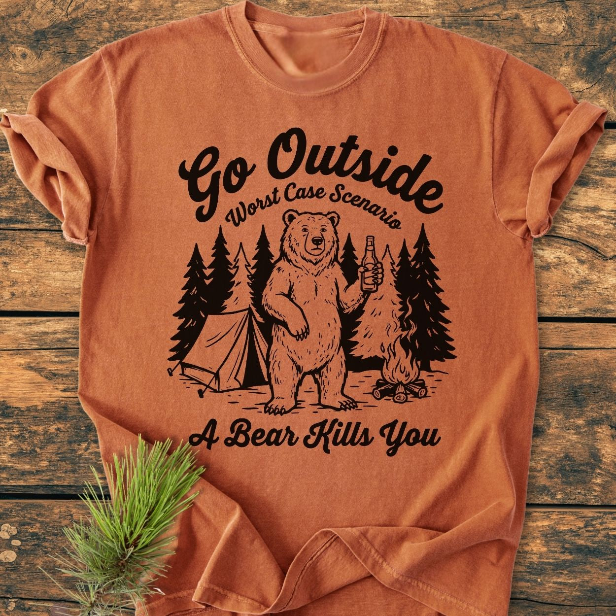Go Outside - Vintage Wash Tee features a black forest camping illustration with a tent, campfire, and bear on rust-orange fabric, offering a cozy, relaxed fit with durable double-needle stitching.