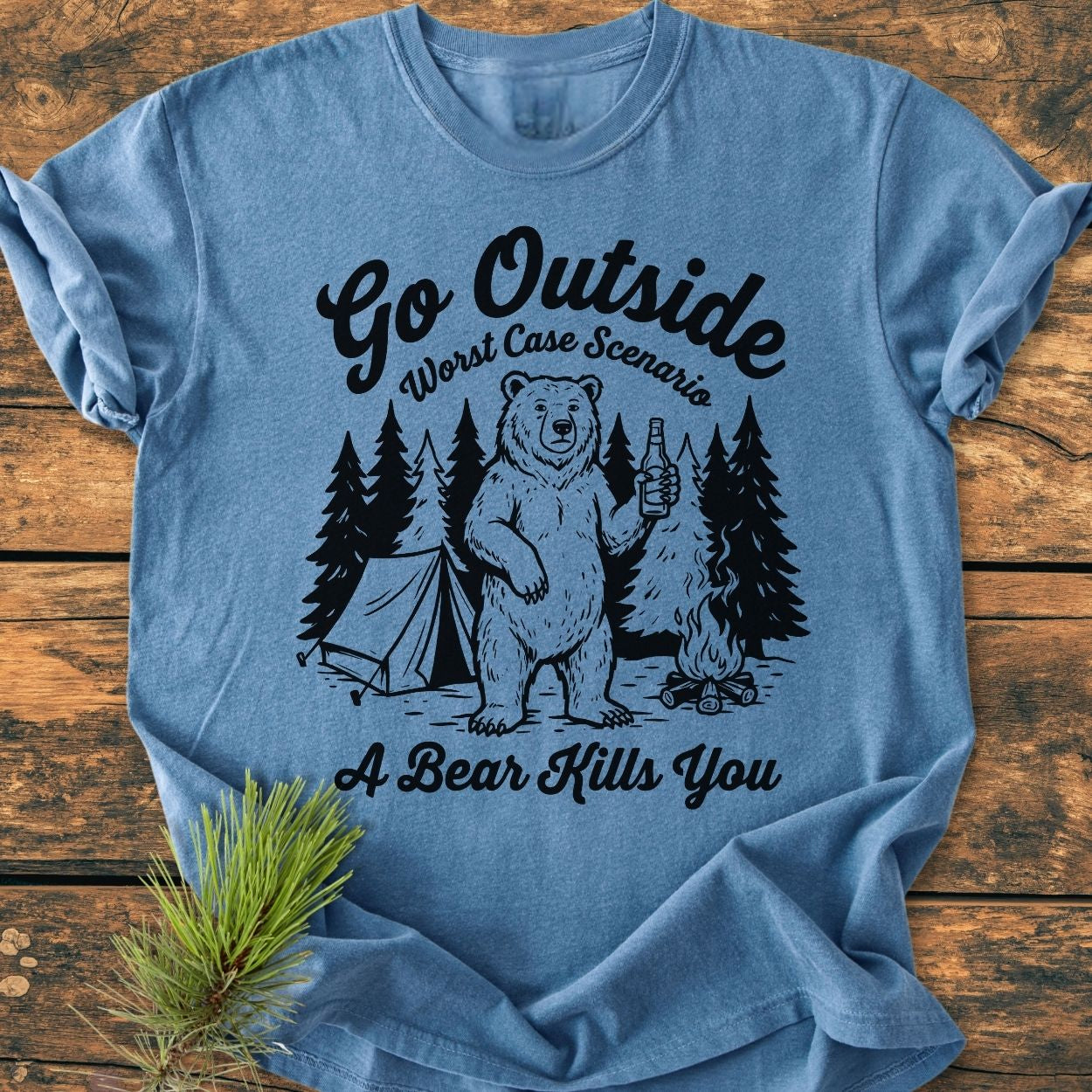 Go Outside - Vintage Wash Tee features a playful graphic of a bear with a bottle, campsite scene, and humorous text, all printed on a light-blue short-sleeve T-shirt, highlighting outdoor adventure.