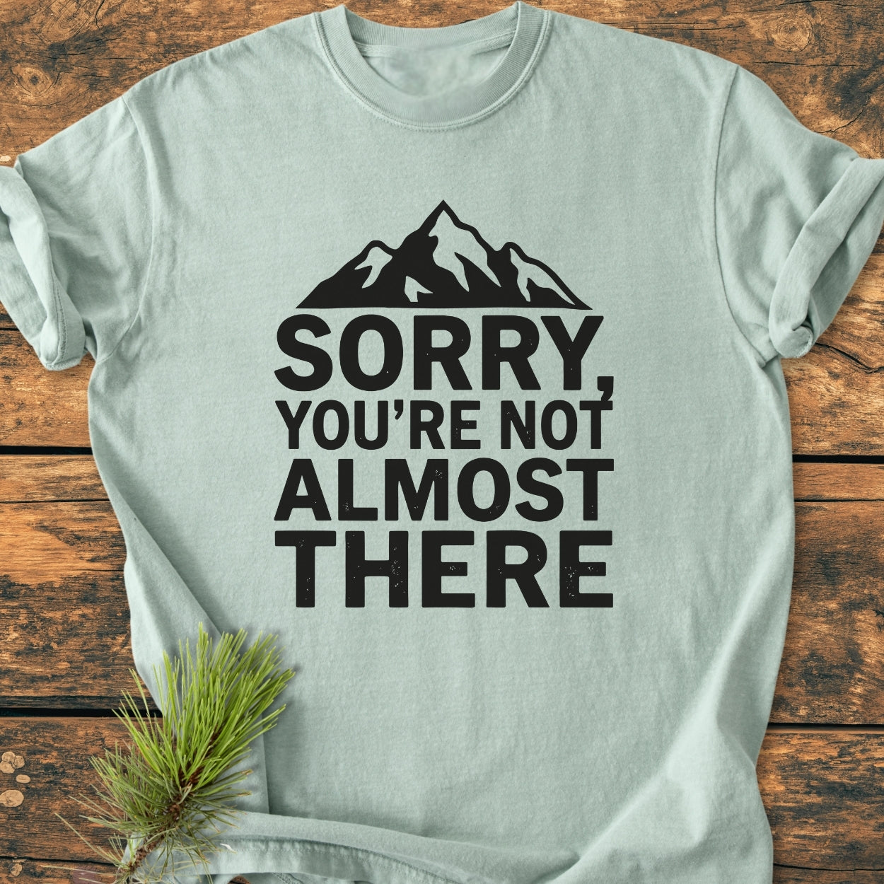 Sorry You're Not Almost There - Vintage Wash Tee features a black mountain silhouette and bold text on a laid-flat light-blue shirt, showcasing its relaxed fit and soft-washed, garment-dyed fabric.