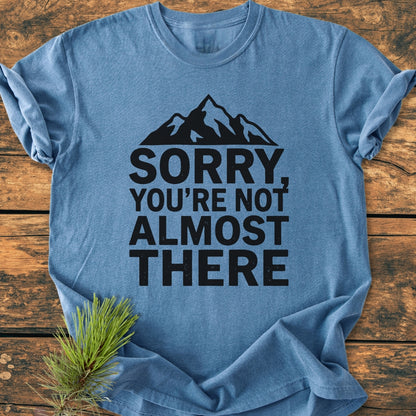 Heather-blue tee on wood features a mountain silhouette with SORRY, YOU’RE NOT ALMOST THERE. Crafted from 100% ring-spun cotton, this vintage wash tee offers a relaxed, comfortable fit.