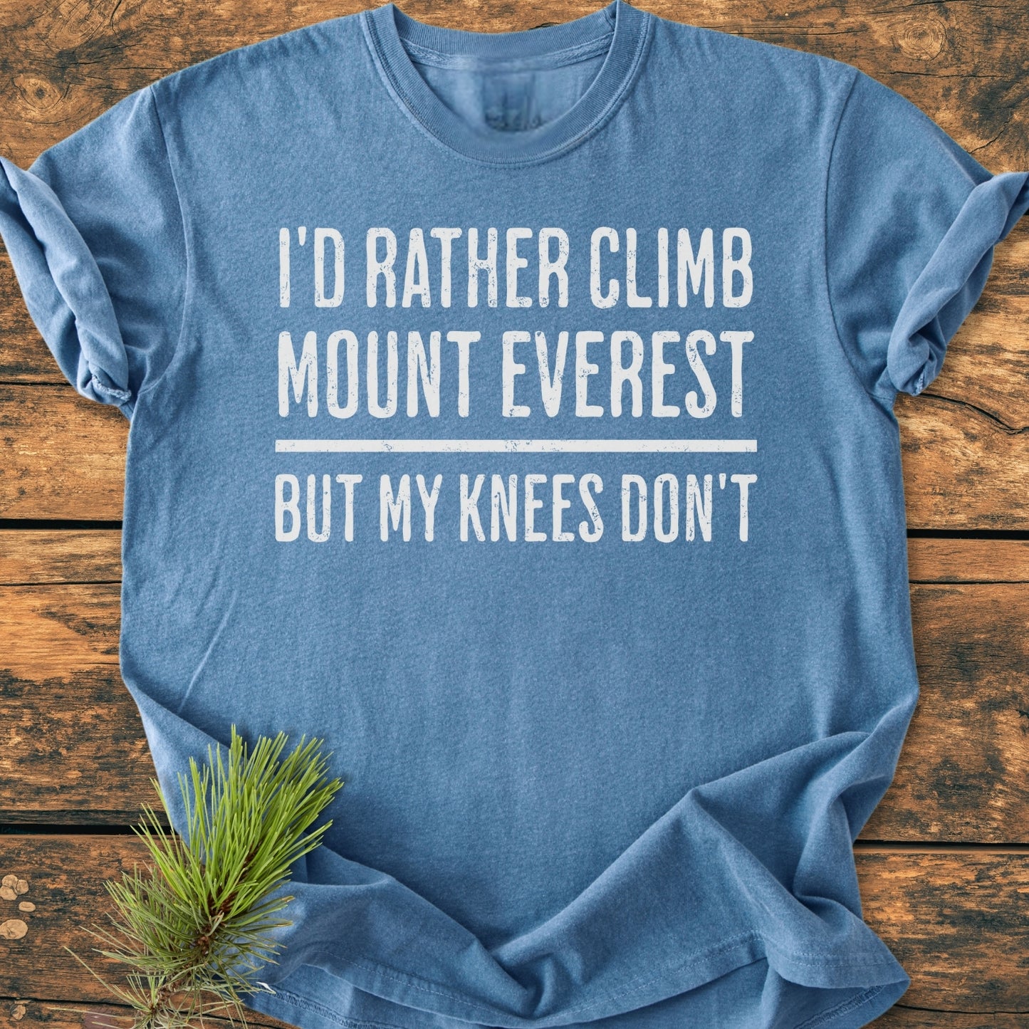 Heather-blue I'd Rather Climb Mount Everest - Vintage Wash Tee with distressed white text, laid on rustic wood, pine sprig near hem. Soft, relaxed fit, durable, made of 100% ring-spun cotton.