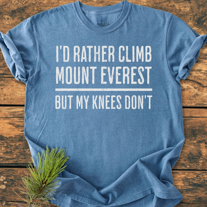 Heather-blue I'd Rather Climb Mount Everest - Vintage Wash Tee with distressed white text, laid on rustic wood, pine sprig near hem. Soft, relaxed fit, durable, made of 100% ring-spun cotton.