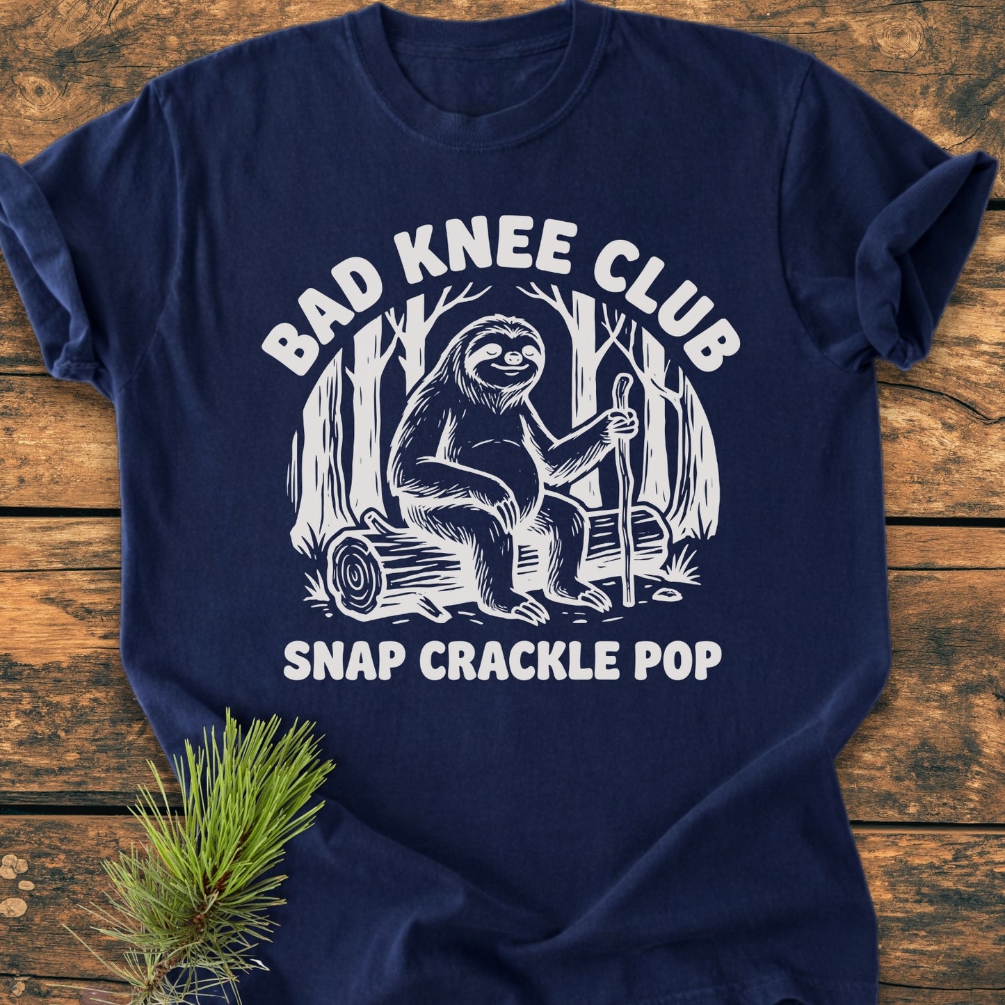 Bad Knee Club - Vintage Wash Tee features a contented sloth with a walking stick, screen-printed in white, on the front of a navy-blue T-shirt, emphasizing durability and comfort.