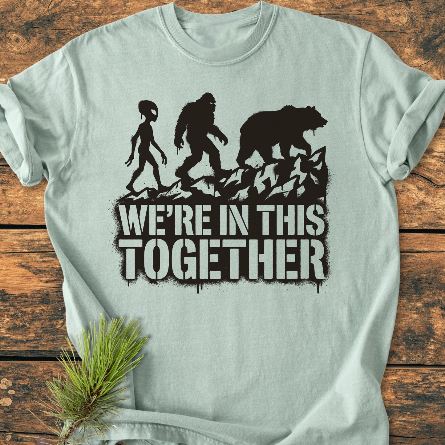 In This Together - Vintage Wash Tee features an alien, Bigfoot, and bear graphic with the slogan “WE’RE IN THIS TOGETHER,” exemplifying the relaxed fit and soft comfort of this garment-dyed, ring-spun cotton shirt.