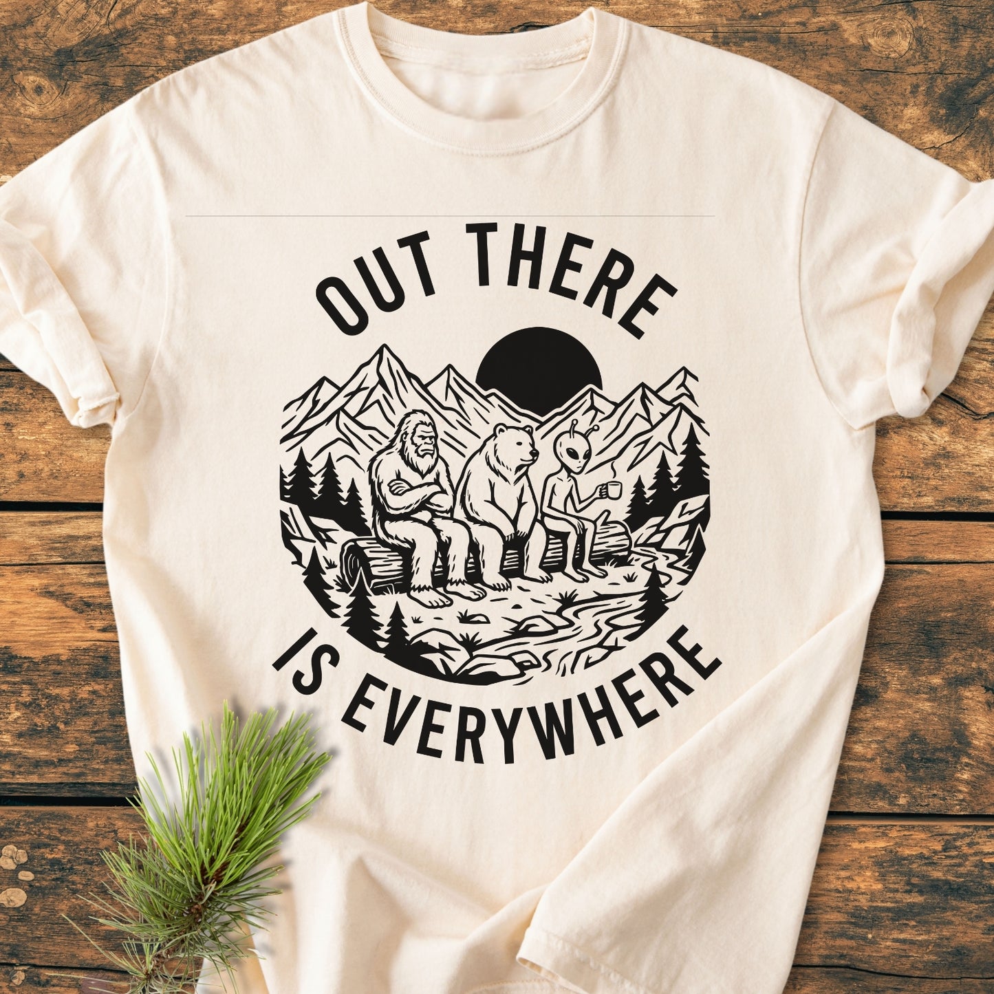 Out There Is Everywhere - Vintage Wash Tee features a whimsical wilderness scene with Bigfoot, a bear, and an alien. Cream-colored, relaxed fit, made from soft, durable ring-spun cotton.