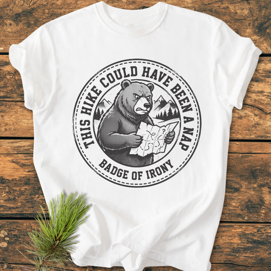 Could Have Been A Nap - Vintage Wash Tee featuring a black circular graphic with a bear, mountains, and trees. Text reads “THIS HIKE COULD HAVE BEEN A NAP.” Laid on a wooden surface with a pine branch.