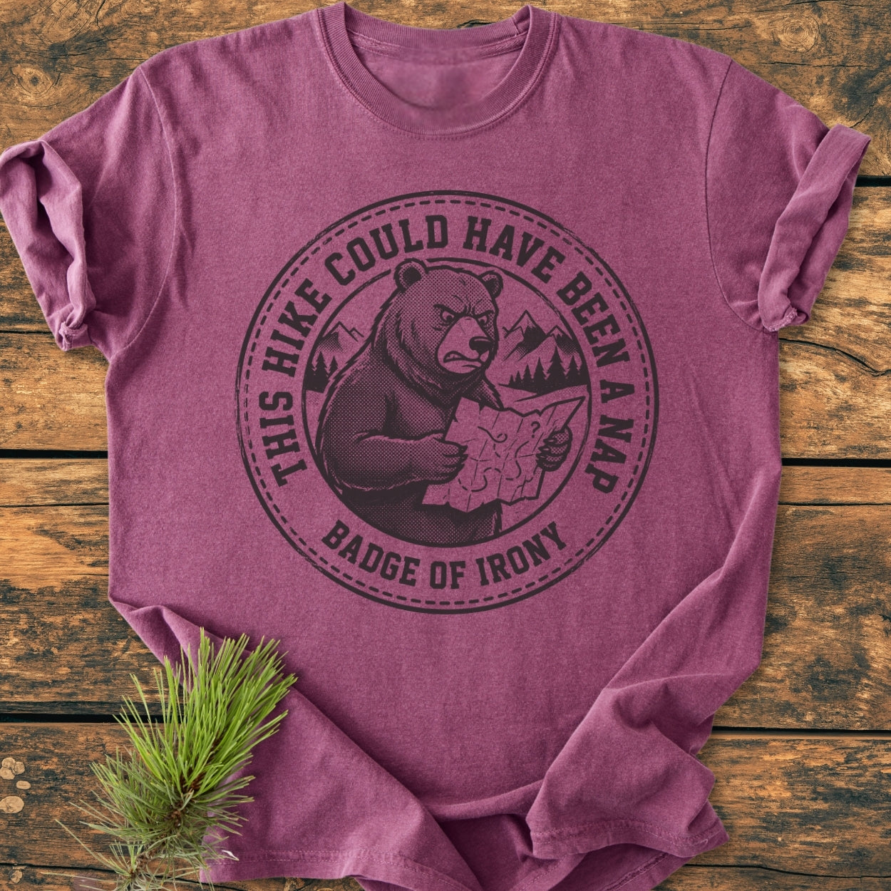 Could Have Been A Nap - Vintage Wash Tee: Purple-mauve T-shirt on wooden surface with pine branch, featuring a circular logo of a bear with a map, mountain-forest scene, and ironic text.