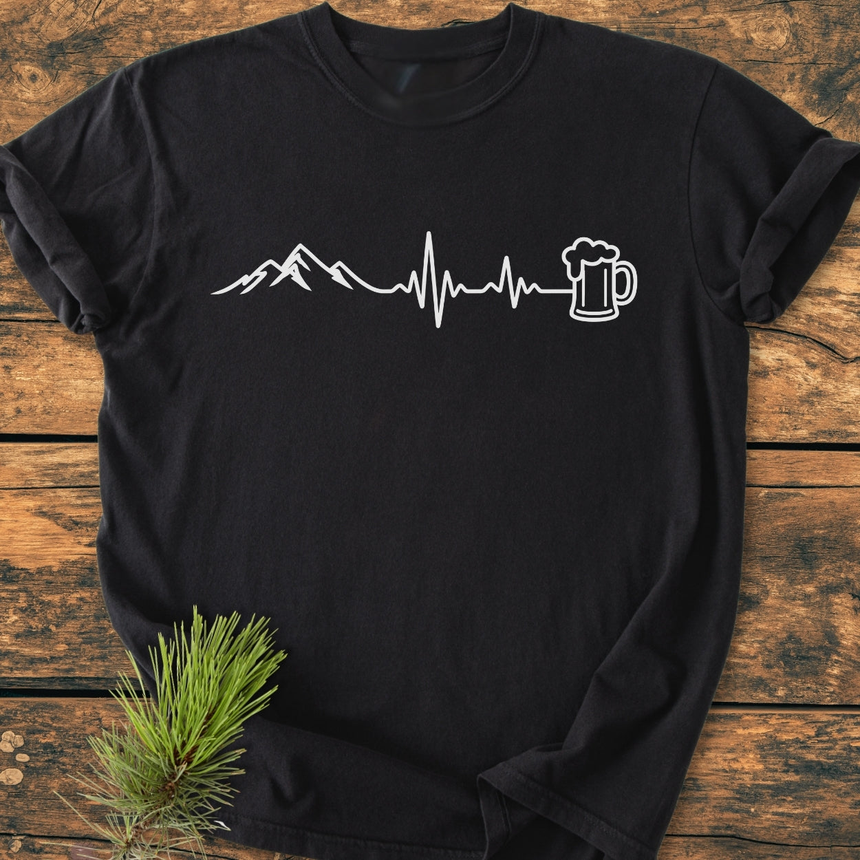 Mountains And Beer - Vintage Wash Tee features a stylized mountain, heartbeat line, and beer mug graphic on a soft, black Comfort Colors T-shirt, highlighting its cozy, relaxed fit and durable design.