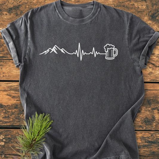 Mountains And Beer - Vintage Wash Tee features a white mountain and beer mug design on dark charcoal-gray. Laid on wood, this relaxed-fit, soft-washed, garment-dyed tee is perfect for everyday comfort.
