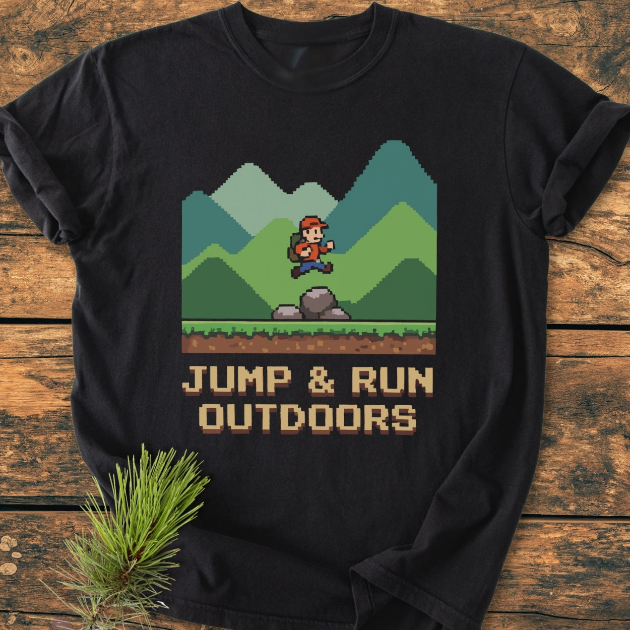 Jump And Run Outdoors - Vintage Wash Tee featuring an 8-bit hiker graphic on black fabric, laid on wood with pine sprig. Soft, relaxed fit, pre-shrunk cotton for comfort and durability.