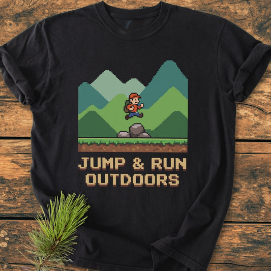 Jump And Run Outdoors - Vintage Wash Tee featuring an 8-bit hiker graphic on black fabric, laid on wood with pine sprig. Soft, relaxed fit, pre-shrunk cotton for comfort and durability.
