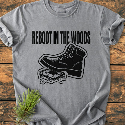 Reboot In The Wood - Vintage Wash Tee featuring a hiking boot graphic rebooting a microchip, laid on a wooden surface with pine needles accentuating the outdoor theme.
