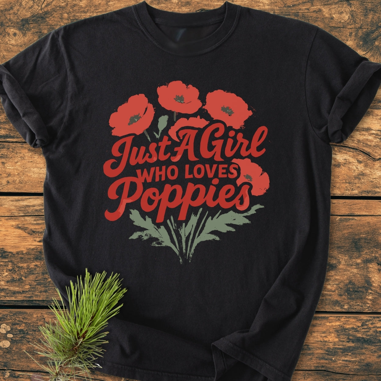 Just A Girl Who Loves Poppies - Vintage Wash Tee features a vibrant red poppy bouquet design on a black T-shirt, styled with bold red script, laid out on a rustic wood surface.