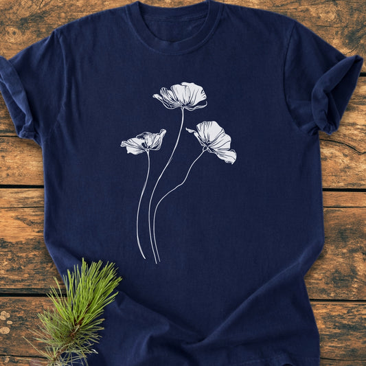 Delicate Poppies - Vintage Wash Tee features a navy-blue T-shirt with three white line-drawn poppy-style flowers, laid on a rustic wooden surface, emphasizing its relaxed, cozy fit and durable craftsmanship.