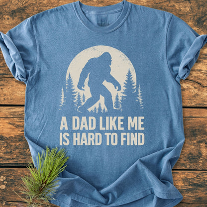 Vintage Bigfoot Dad - Vintage Wash Tee featuring a Bigfoot silhouette against a full moon and pine trees, captioned “A DAD LIKE ME IS HARD TO FIND,” styled with a pine sprig.