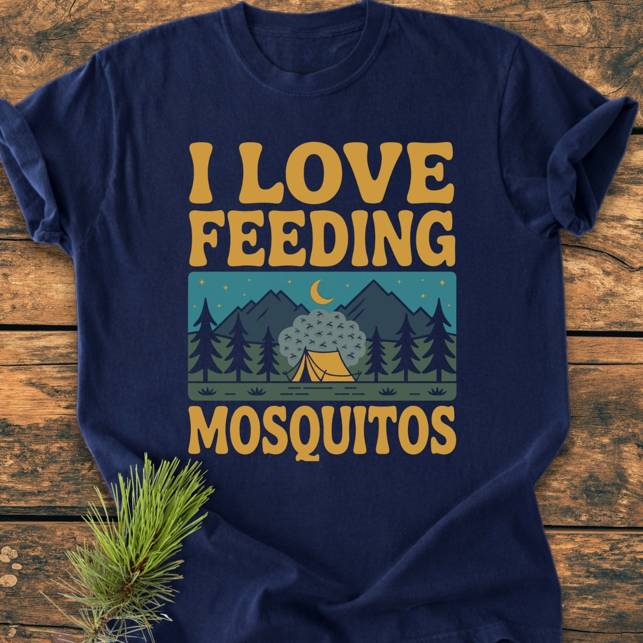 I Love Feeding Mosquitos - Vintage Wash Tee: Navy-blue T-shirt with gold-yellow lettering and retro camping scene, showcasing a tent, pine trees, and buzzing mosquitoes, styled with a pine sprig.
