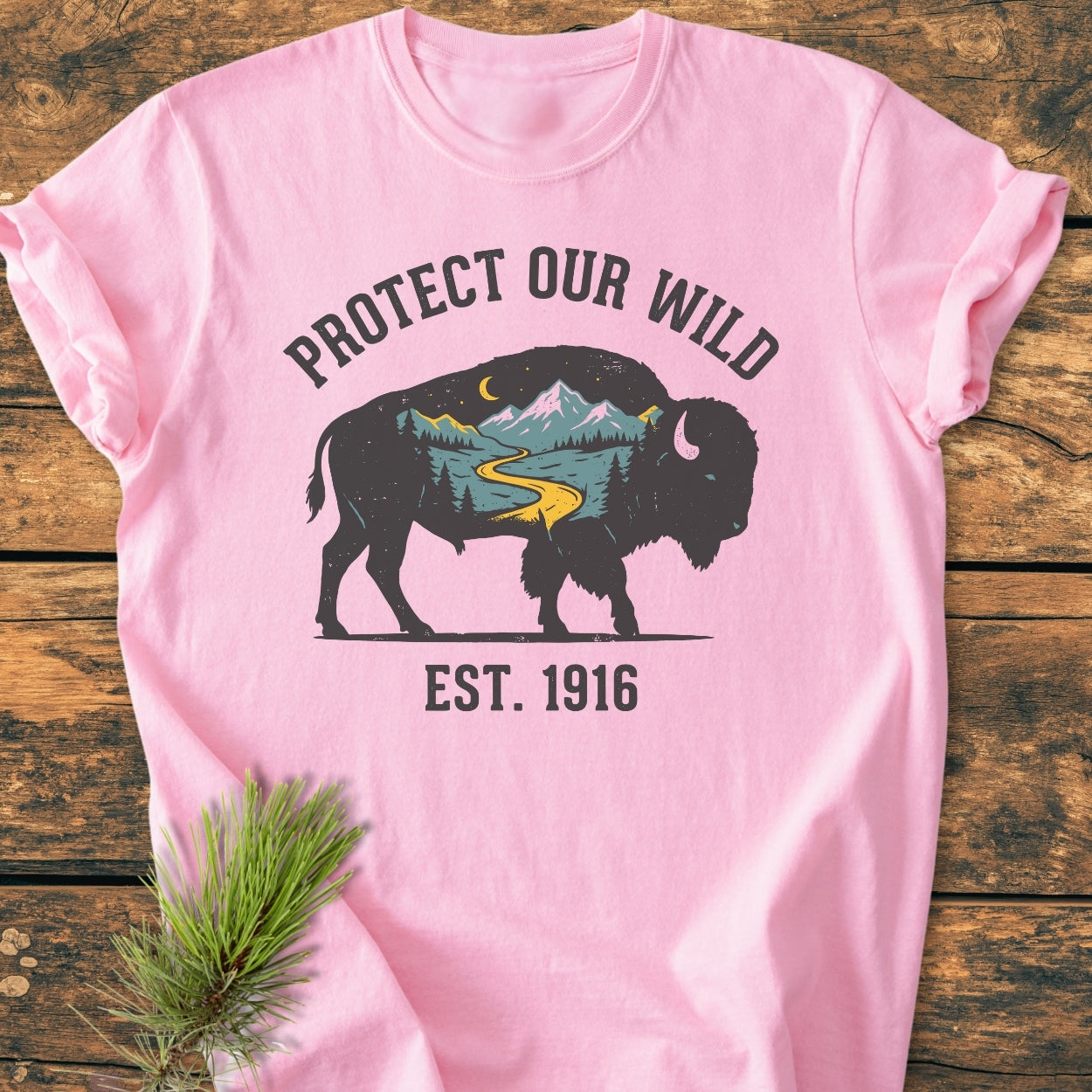 Protect Our Wild - Vintage Wash Tee features a bison silhouette with a nature scene, PROTECT OUR WILD text above, and EST. 1916 below, displayed on a light pink, soft-washed, ring-spun cotton T-shirt.