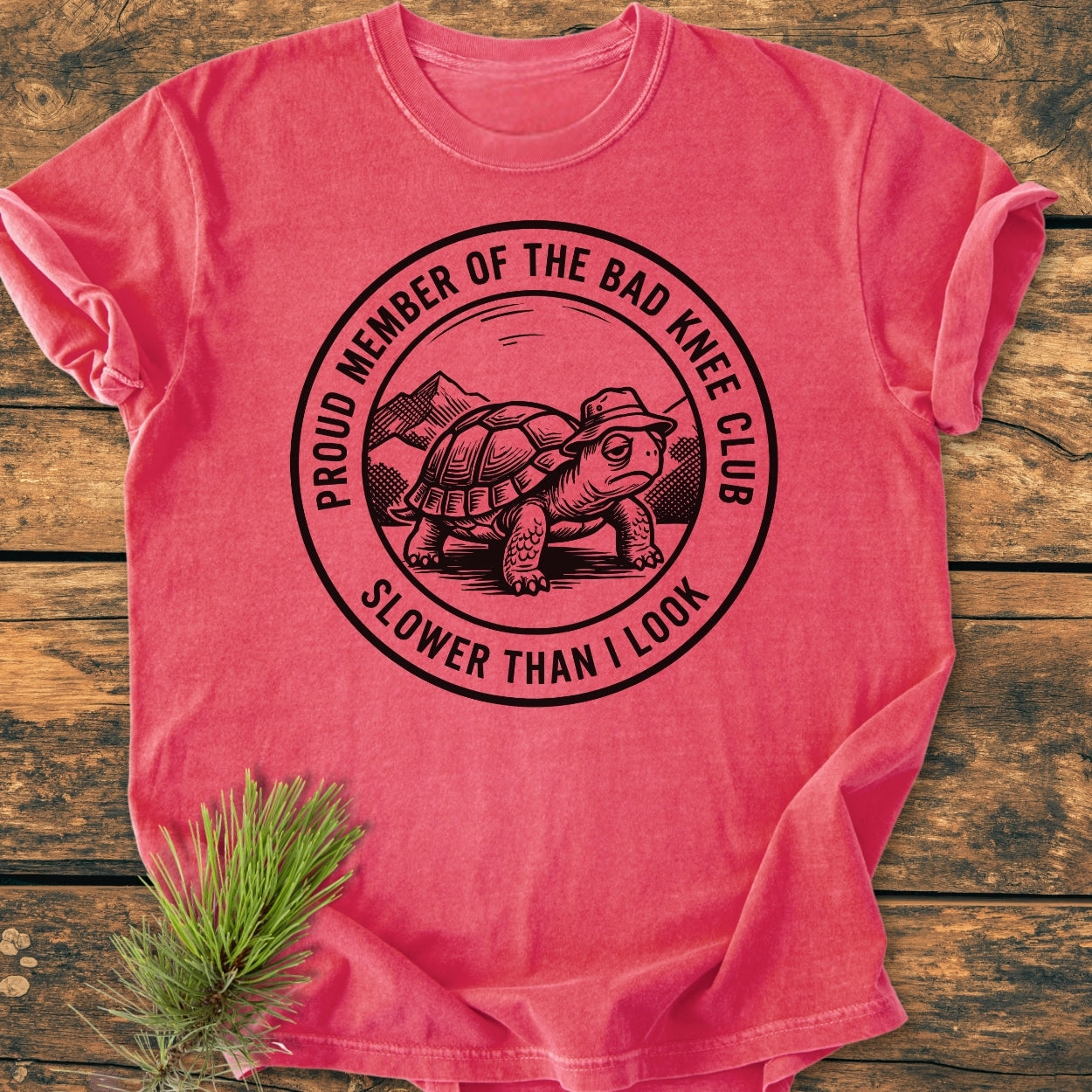 Bad Knee Club - Vintage Wash Tee features a black graphic of a turtle with a hat in a mountain scene, text reads “Proud Member of the Bad Knee Club” and “Slower Than I Look.”