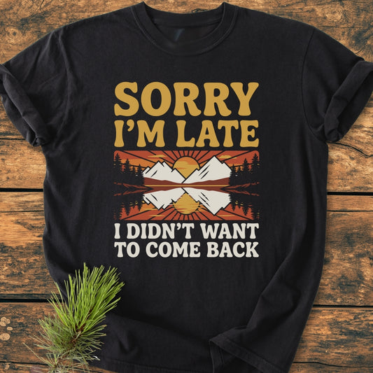Sorry I'm Late - Vintage Wash Tee features a mountain-and-forest print with sunrise/sunset over peaks. The black, soft-washed, ring-spun cotton T-shirt offers a relaxed fit, perfect for everyday comfort.