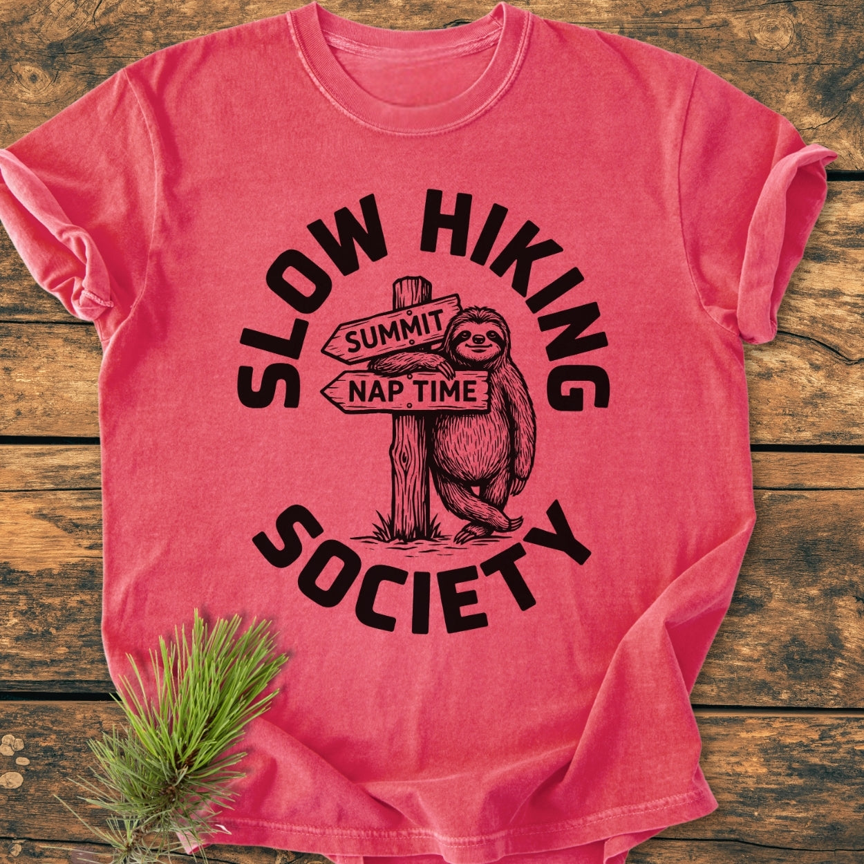 Slow Hiking Society - Vintage Wash Tee features a cartoon sloth with a trail sign graphic, Summit and Nap Time, encircled by the playful slogan on a coral-red T-shirt.