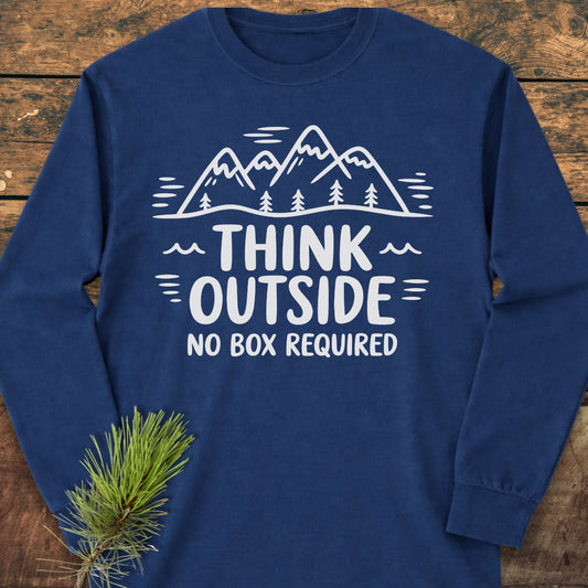 Think Outside Long-Sleeve Tee with white mountain and tree line-drawing and slogan on chest, laid flat on wood with pine sprig nearby. Made of 100% ring-spun cotton for comfort.