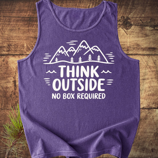 Purple Think Outside Tank Top featuring a white graphic of stylized mountains and pine trees with the slogan, laid flat on wood surface; sprig of pine needles tucked under the edge.