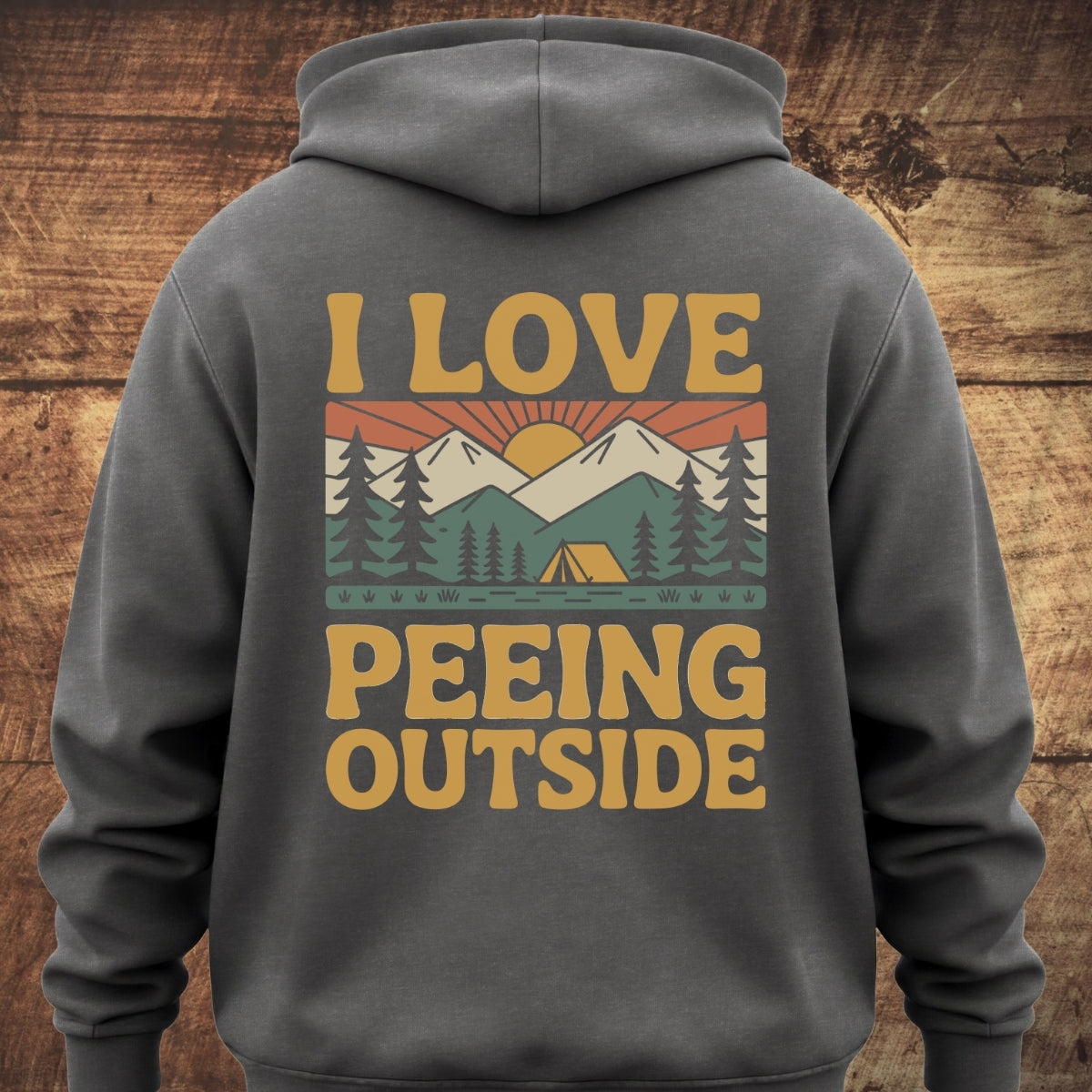 I Love Peeing Outside Hoodie BACKPRINT featuring a retro outdoor scene with sun, mountains, and tent. Bold yellow text completes the design on a dark gray, garment-dyed, unisex hoodie.