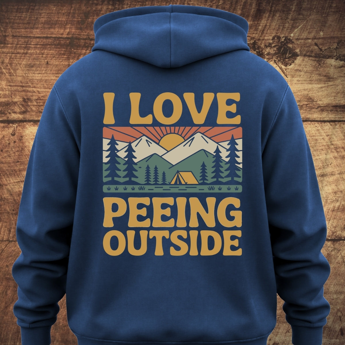 I Love Peeing Outside Hoodie BACKPRINT features a retro camp scene with mountains, pines, a tent, and rising sun, complemented by bold text, perfect for outdoor enthusiasts seeking comfort and style.