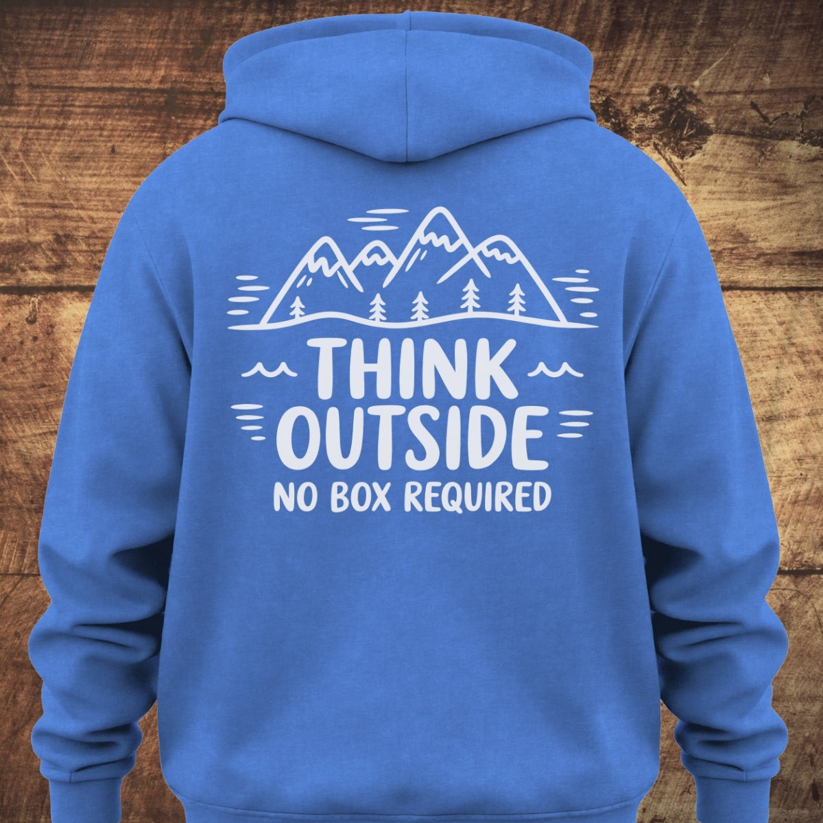Back view of the Think Outside Hoodie BACKPRINT featuring white line-art of mountains and trees with the slogan THINK OUTSIDE NO BOX REQUIRED on blue fabric, highlighting its relaxed, trail-ready design.