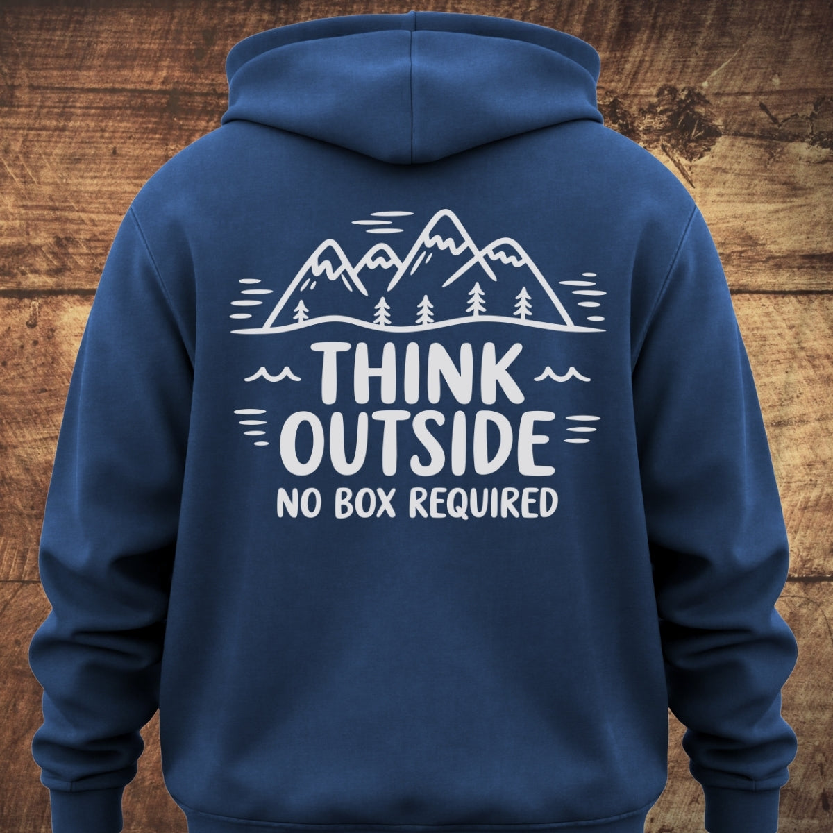 Back view of the Think Outside Hoodie BACKPRINT, featuring a white mountain-and-tree graphic above the slogan THINK OUTSIDE NO BOX REQUIRED, displayed on a navy-blue garment-dyed unisex hoodie.