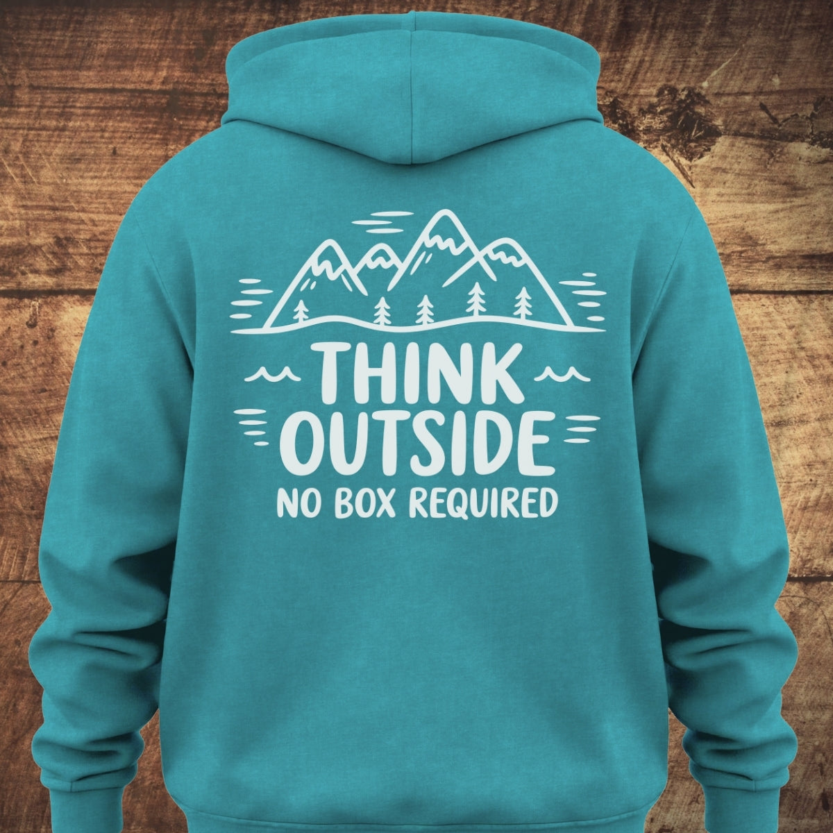 Back view of the Think Outside Hoodie BACKPRINT, featuring a white graphic of mountains and trees with the slogan THINK OUTSIDE NO BOX REQUIRED on a soft, garment-dyed teal hoodie for relaxed, trail-ready comfort.