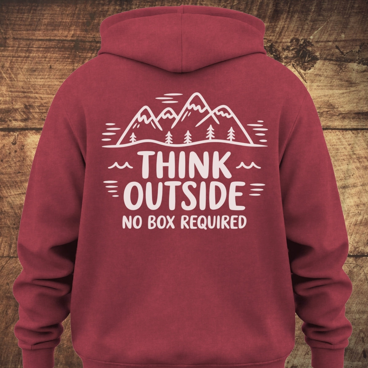 Back view of Think Outside Hoodie BACKPRINT featuring a white line-drawing of a mountain range with pine trees, and the slogan THINK OUTSIDE NO BOX REQUIRED printed below on maroon fabric.
