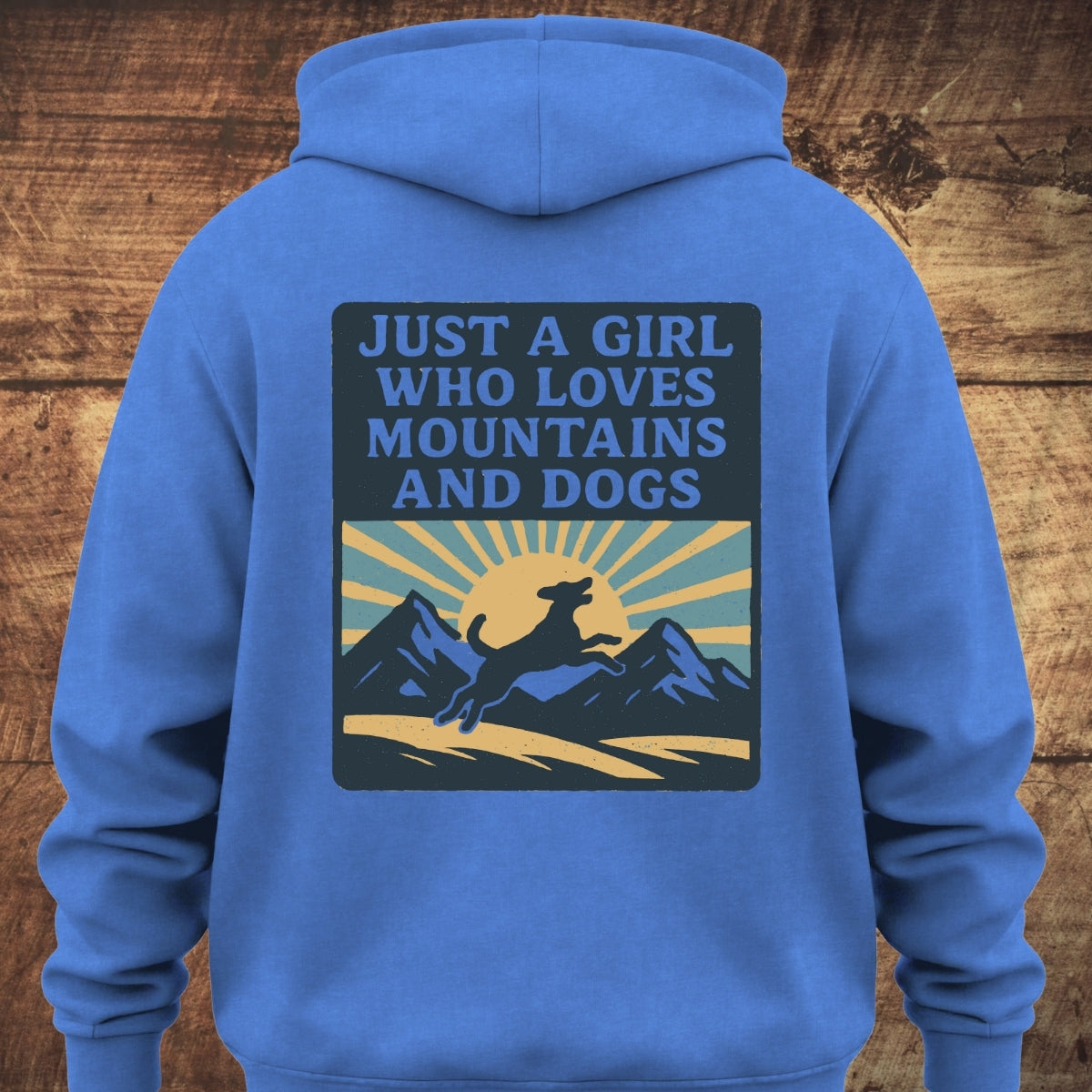 Just A Girl Who Loves Dogs Hoodie BACKPRINT features a retro graphic with a sunrise, mountains, and a leaping dog silhouette, capturing adventurous spirit on a cozy garment-dyed, unisex hoodie.