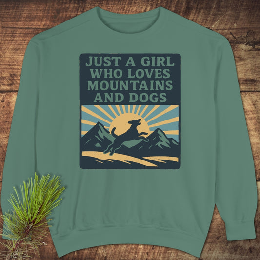 Just A Girl Who Loves Dogs Sweatshirt featuring a vintage graphic of a dog and mountains, laid flat with a pine branch prop. Unisex, relaxed fit with embroidery options, ideal for comfort and style.