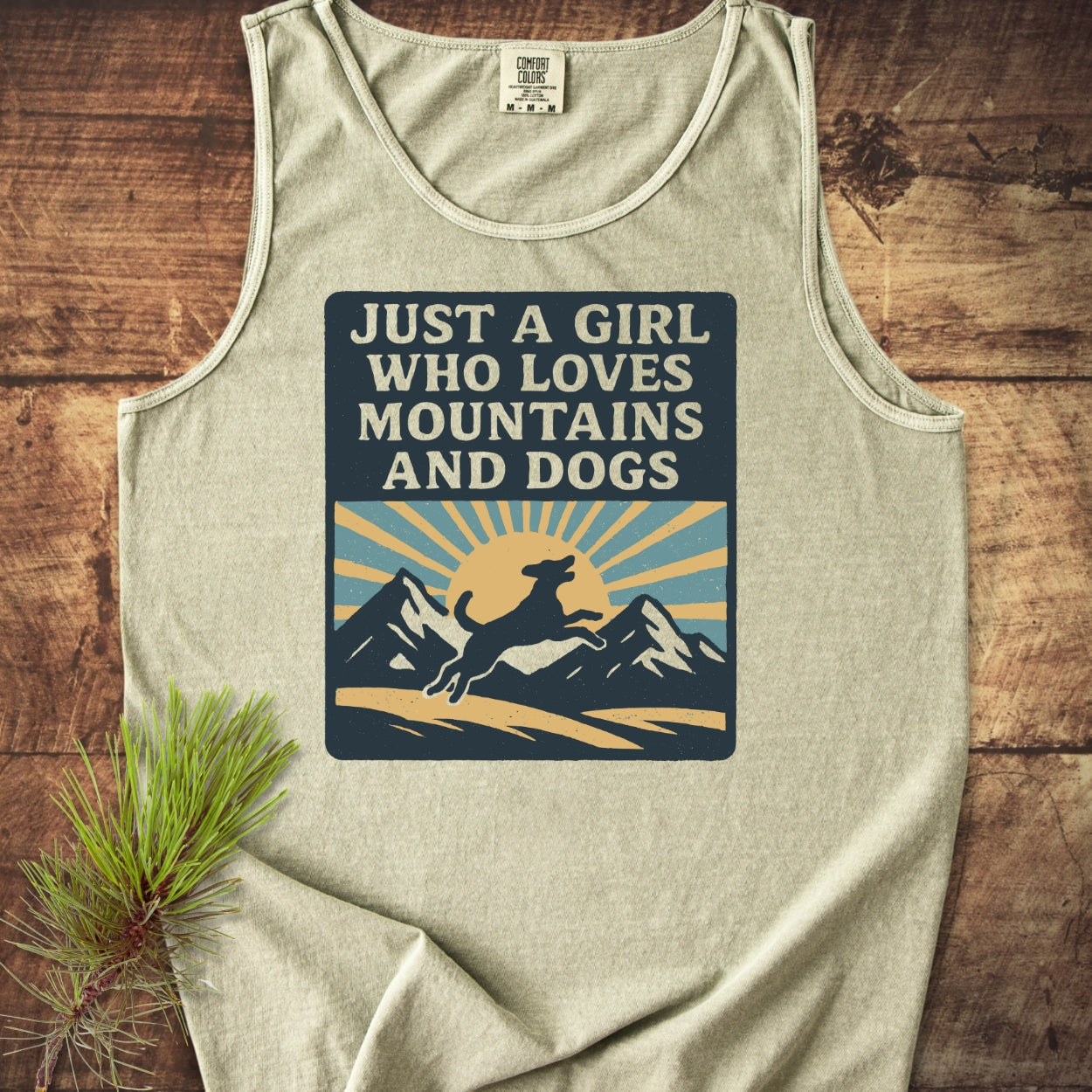 Just A Girl Who Loves Dogs Tank Top features a bold graphic with a dog, mountains, and sun. Made from ring-spun US cotton, it offers a relaxed fit and eco-friendly vibrant dyes.