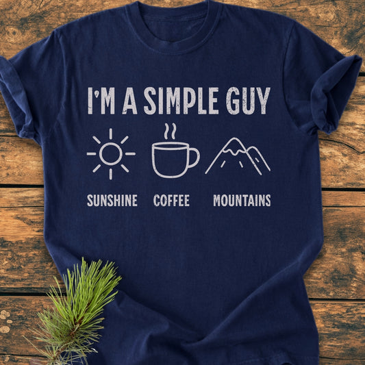 I'm A Simple Guy - Sunshine Coffee Mountains - Vintage Wash Tee displayed on wood, featuring distressed white text and icons of a sun, coffee mug, and mountains; crafted from garment-dyed, 100% ring-spun cotton.