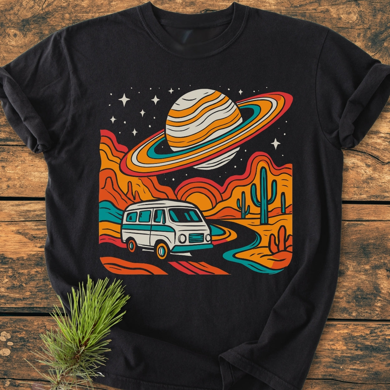 Psychedelic Van Journey - Vintage Wash Tee: Black T-shirt featuring a retro desert scene with a camper van, mesas, cacti, a setting sun, and a starry sky with a ringed planet.